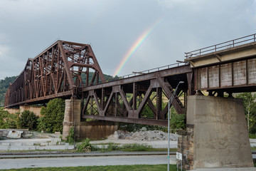 Rainbow passing behind large steel girder train bridge
