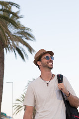 Modelo paseando delante de la playa con sombrero y gafas