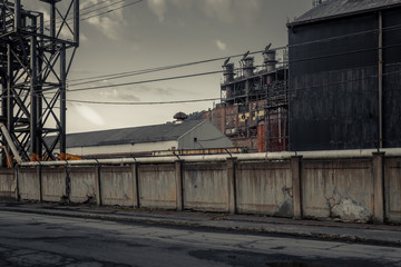Fototapeta premium Angled view of giant smoke stacks behind a large concrete wall of an abandoned factory