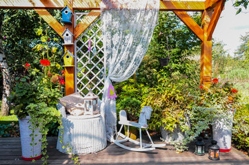 Altanka z tarasem w ekologicznym ogrodzie. Miejsce do odpoczynku w pieknym letnim ogrodzie. Konik wypoczynkowy w ogrodzie - obrazy, fototapety, plakaty