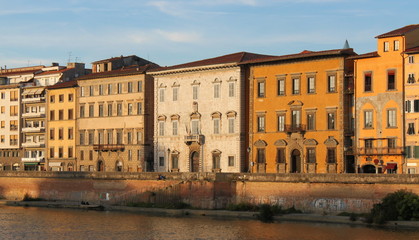Fototapeta na wymiar Colorful palazzo facades at Arno river in Pisa, Italy, on a sunny evening