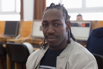 Naklejka premium University mixed race Students, african, american and european during the class in computer room. Resolving problems together. African student looking into camera.