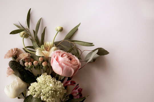 Horizontal image of fresh cut, pastel flowers and greenery on a white background with copy space