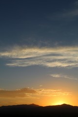 Fototapeta premium Heavens illuminate as sun sets over the Hexie Mountains of Joshua Tree National Park. Although much of the range is within the Mojave, its edges transition and integrate with the Colorado Desert.
