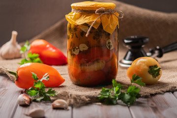 Jar of pickled peppers on a rustic wooden background. Pickled and canned product. Next ingredients for cooking and a machine for spinning