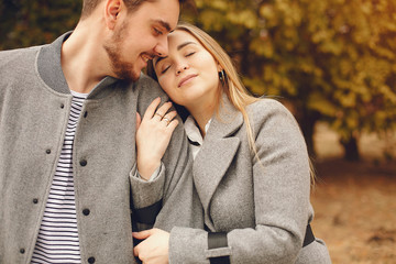Fototapeta premium Couple in a park. Woman in a gray coat. Man with his wife