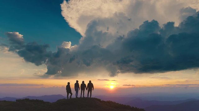 The four people standing on a mountain against the beautiful sunrise