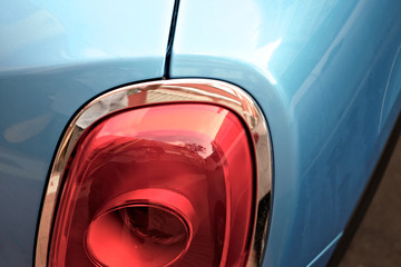 Modern car exterior detail, light pearl blue body and pastel red indicator light.