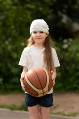 Little girl with long hair with a basketball in her hands