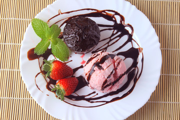 petit gateau with ice cream on white plate with strawberry over rustic wooden table