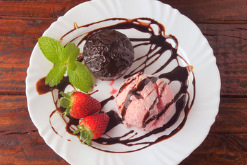 petit gateau with ice cream on white plate with strawberry over rustic wooden table