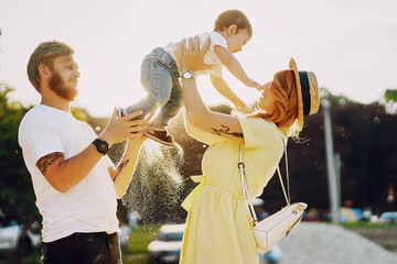 Beautiful red-haired woman with her husband and a wonderful son on a summer park