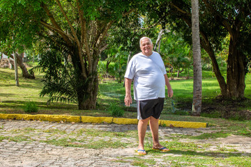 Fat old man walks exercises nature park