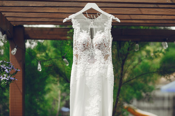 Beautiful wedding dress hangs on the hanger. White dress in a outside