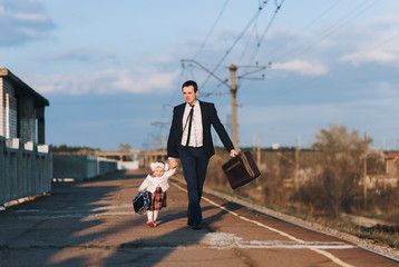 Loving dad and businessman in suit and glasses with a suitcase hurrying to the train, walking with...
