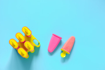 Homemade popsicles. Natural strawberry ice cream in bright plastic molds on blue background with copy space. Top view Flat lay Template for your design
