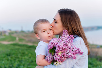 Young loving mother walking with her little son on spring background. Cute child and her mom on...