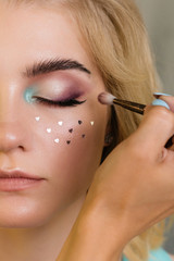 Makeup artist applies eye shadow on moving eyelid model. Creative makeup. Beauty industry. Beauty salon concept
