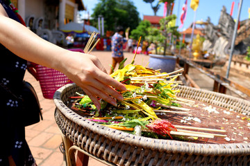 People are bringing flowers and incense candles placed on large trays made of wood placed in front to worship in the Lanna tradition.