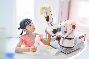 little asian girl touching a robotic machine arm