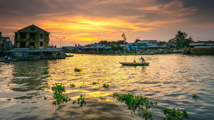 Fototapeta premium Boatman rowing and transporting passengers across the river at sunset Mekong Delta in Soc Trang, Vietnam