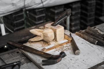 Wood lumber, hand made crafting to be a rabbit shape. Anchored on the workbench around with craving tools such as hammer and axe. (Highlight by saturated color in the center only) 