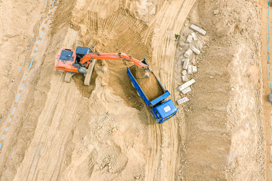aerial top view of industrial machines doing earthmoving works at construction site