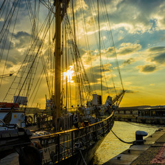 Old sailboat anchored with various colored lights . Sunset