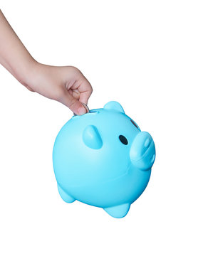 Asian little child hand putting coin in blue piggy bank or colorful empty money savings box isolated on white background with clipping path , top view