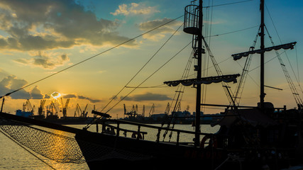Old sailboat anchored with various colored lights . Sunset