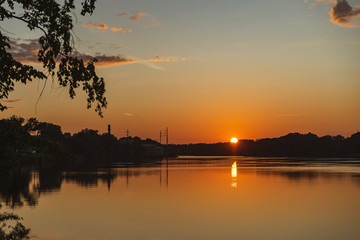 Obraz premium The orange light of a beautiful sunset is reflected in the eagle creek at Marinette,WI.