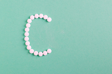 Vitamin C , letter C made from pills on turquoise background