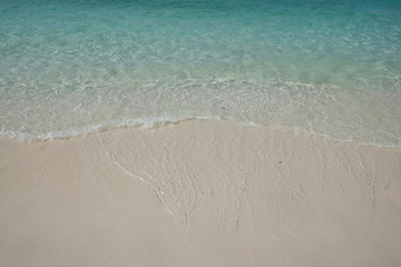Fototapeta na wymiar crystal clear Andaman blue sea with white light waving and smooth sand beach in bright daylight