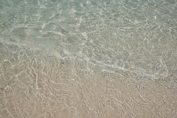 Fototapeta na wymiar crystal clear Andaman sea with smooth curve of water and sand beach beneath it in bright daylight