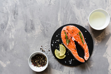 Fresh raw salmon fish steak with spices on dark stone background. Creative layout made of fish, top view, flat lay, mockup, overhead. Healthy food concept