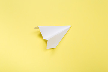Flat lay of white paper plane and blank paper on yellow