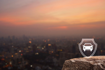 Fototapeta premium Car with shield flat icon on rock mountain over blur of cityscape on warm light sundown, Business automobile insurance concept