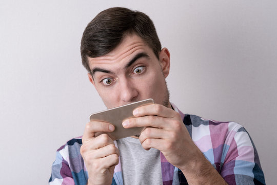 Addicted to smartphone games, close-up portrait on grey