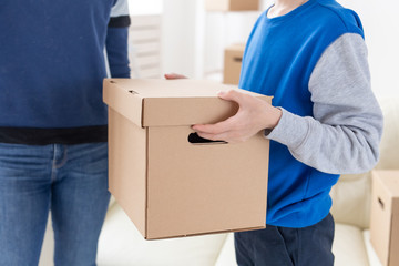 Close-up of teen boy holds a box and a pot of plants while moving to a new apartment. Housewarming and new housing concept.