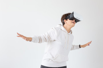 Positive pretty middle-aged woman in a white sweater watching a movie with glasses of virtual reality. The concept of futurism and new technologies.
