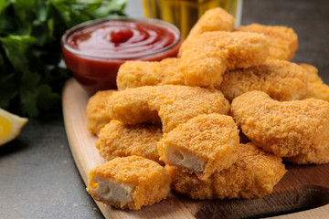 Chicken nuggets with red sauce, ketchup on a wooden board on a brown table. fast food.