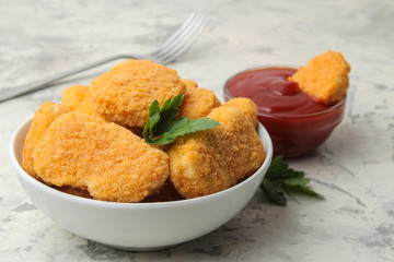 Chicken nuggets in a bowl with red sauce, ketchup on a light concrete table. fast food. close-up.