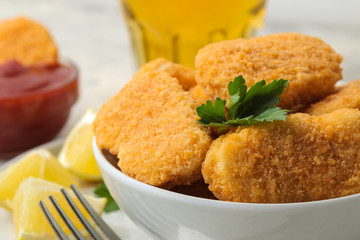 Chicken nuggets in a bowl with red sauce, ketchup and beer on a light concrete table. fast food.
