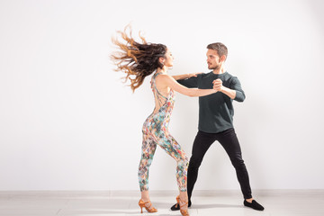 Young couple dancing latin dance bachata, merengue, salsa, kizomba. Two elegance pose over white background with copy space - obrazy, fototapety, plakaty