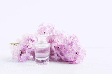 Perfume of lilac in glass bottle on white background. Soft focus with copy space