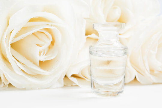 Rose aroma fragrance with bouquet of roses background. Mockup. Sample water glass bottle