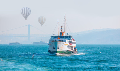 Obraz premium Hot air balloon fly over Bosphorus - Water trail foaming behind a passenger ferry boat in Bosphorus, Istanbul, Turkey