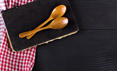 napkin, a recipe book and wooden spoon on a black background