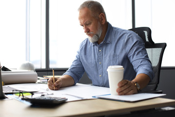 Good looking mature architect drawing something while working in the office.