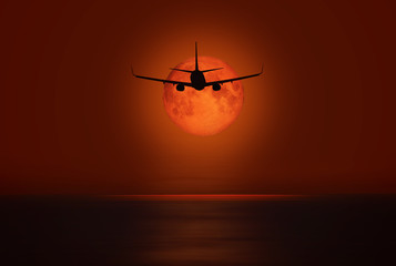 Airplane flying above tropical sea at sunset